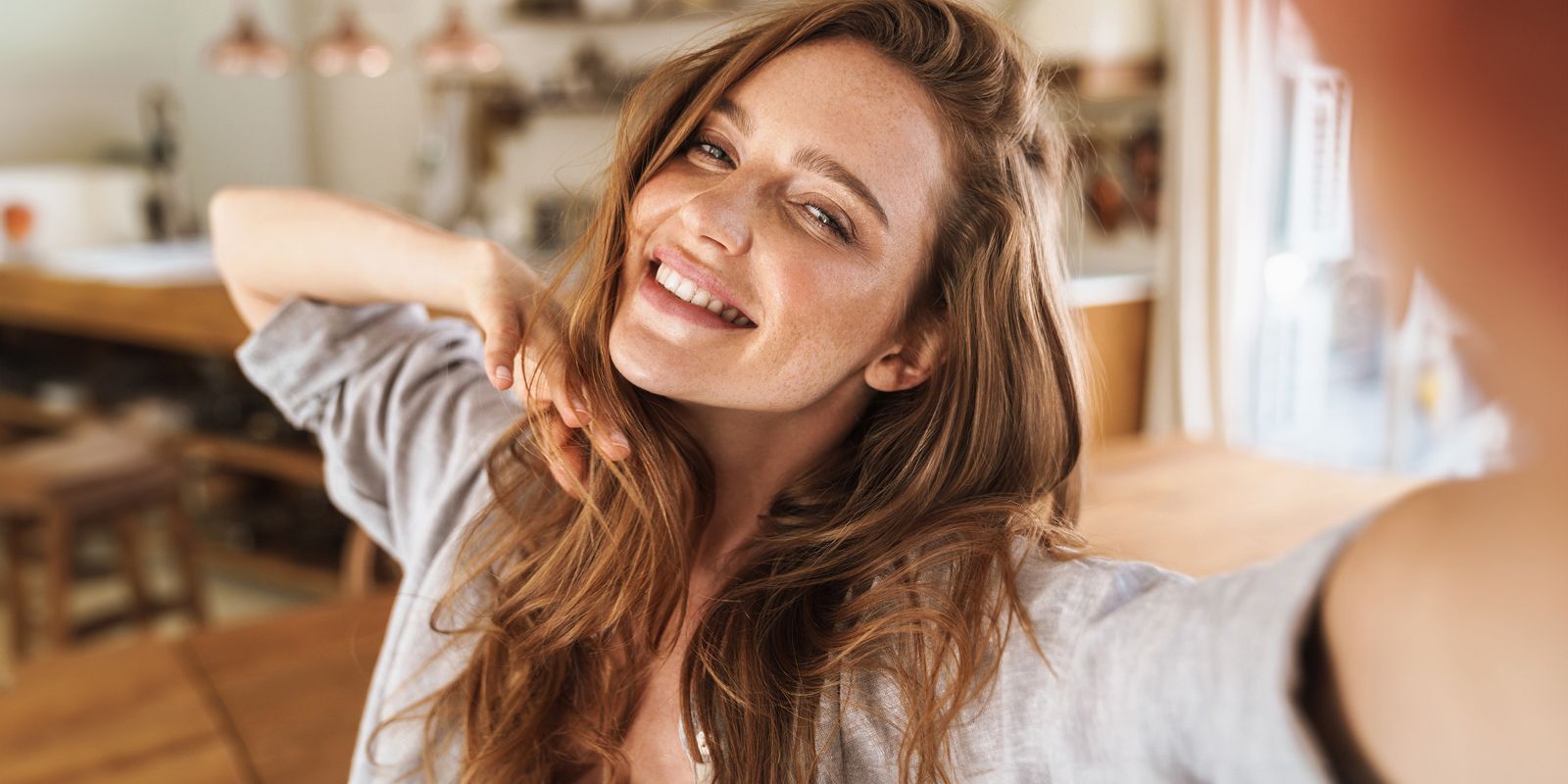 Woman in soft lighting with sheer fabric backdrop.