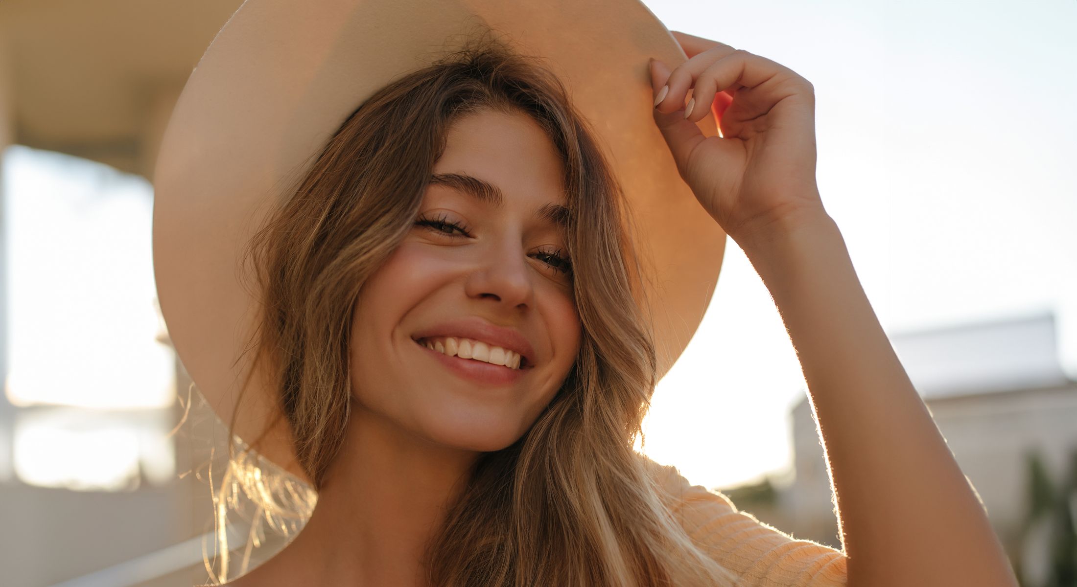 Smiling woman wearing a wide-brimmed hat.