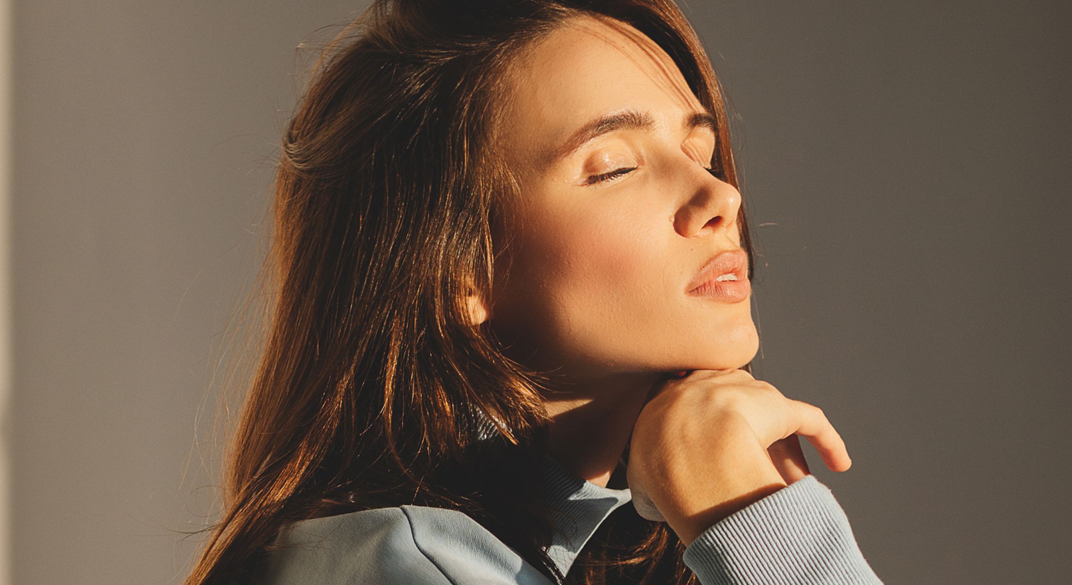 Woman with eyes closed in soft lighting.