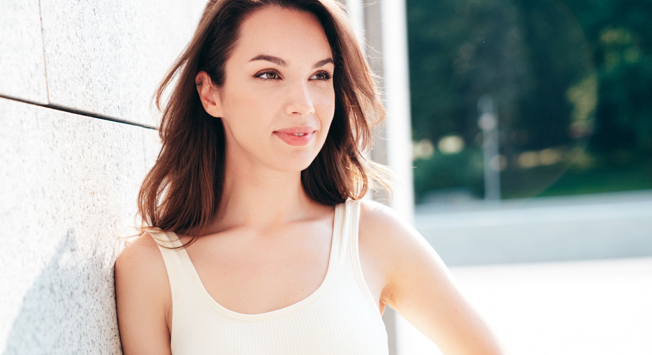 Woman smiling against a light-colored wall.