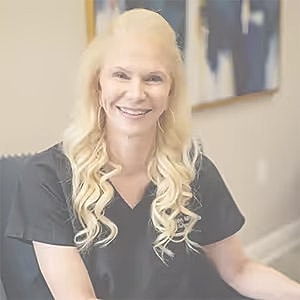 Professional woman smiling against gray background.