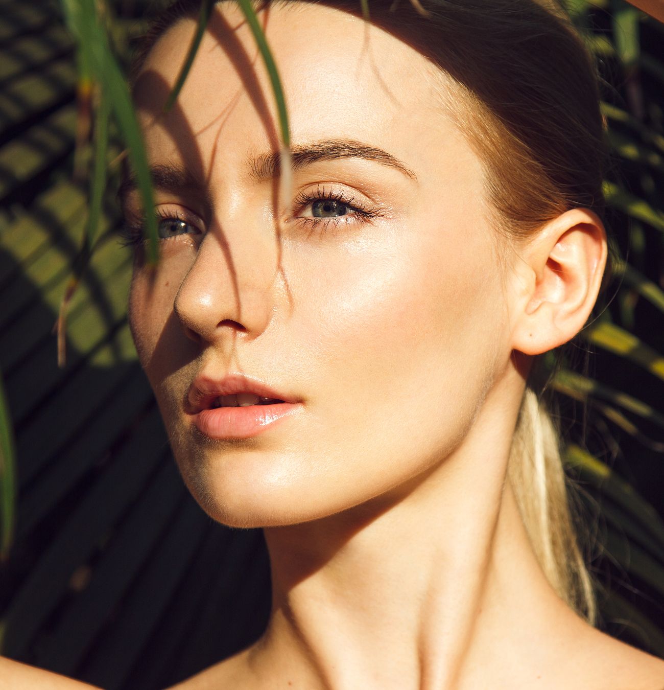 Portrait of a woman with natural lighting and greenery.