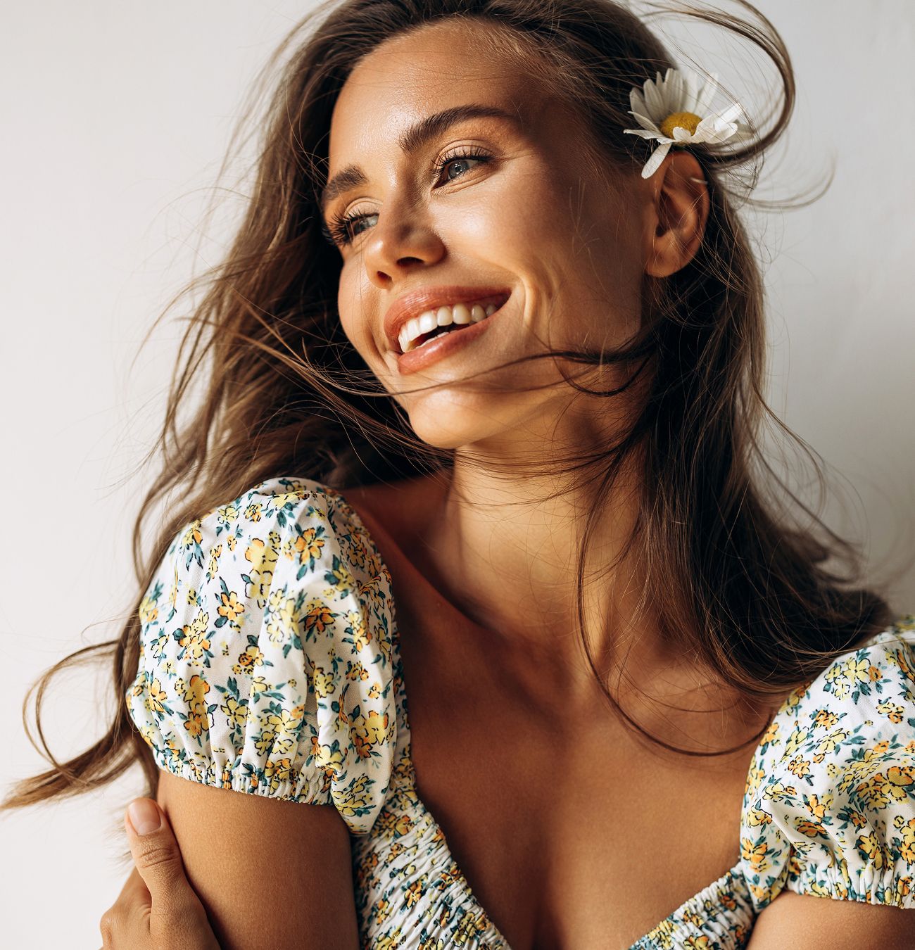 Smiling woman with flowing hair and flower.