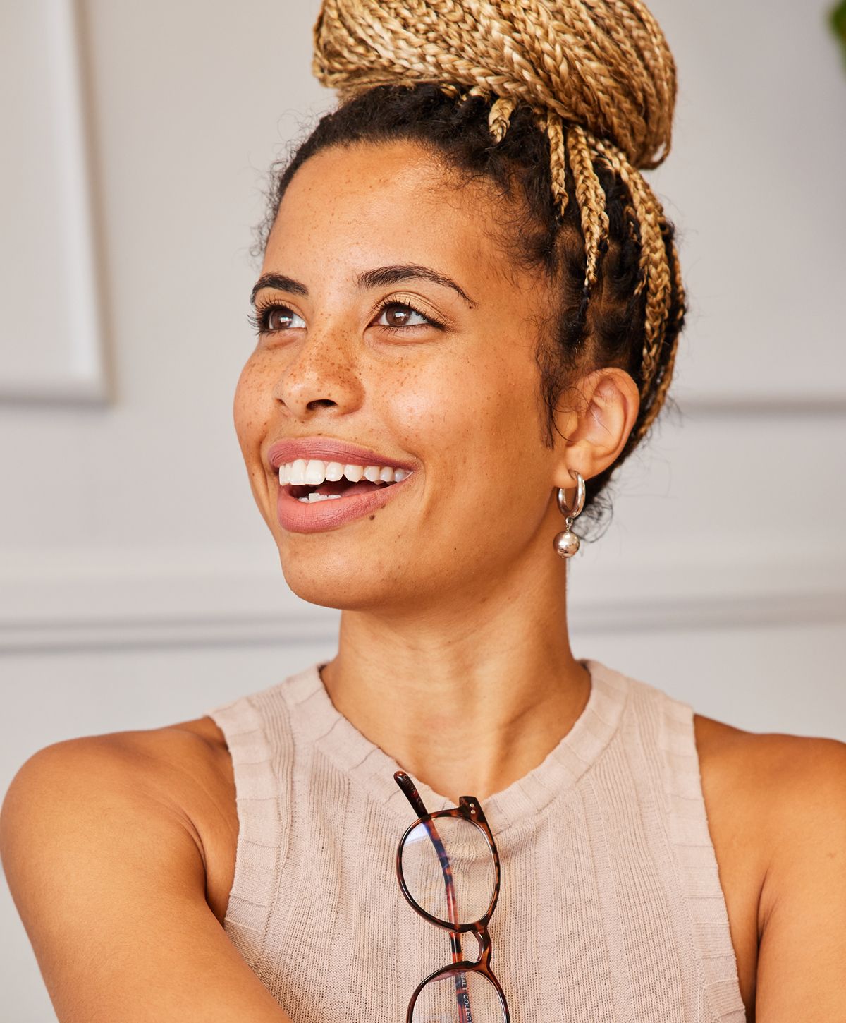 Smiling woman with braided hair and glasses.