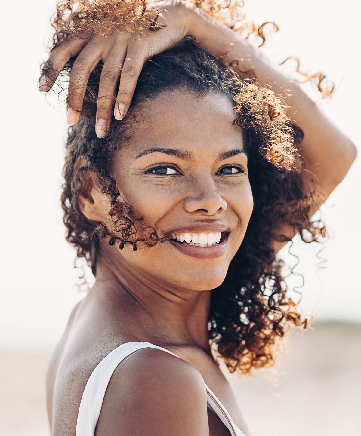 Smiling woman with curly hair outdoors.