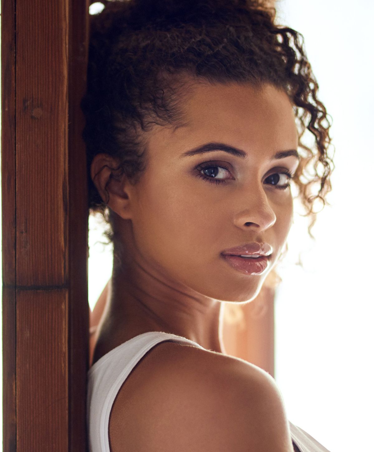 Woman with curly hair, softly looking back.