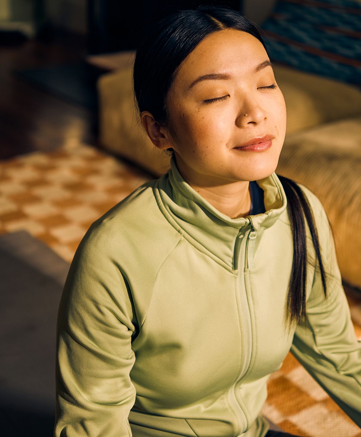Woman meditating indoors with closed eyes.