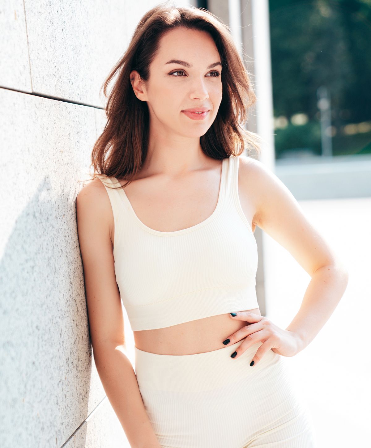 Woman in a white outfit against a light wall.