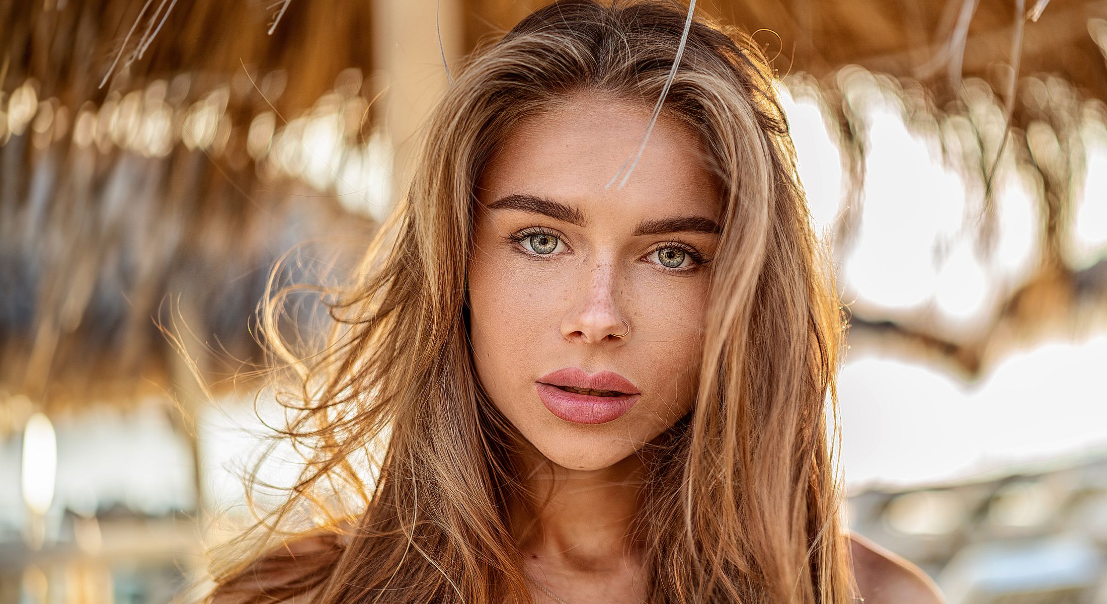 Person with freckles smiling and touching face.