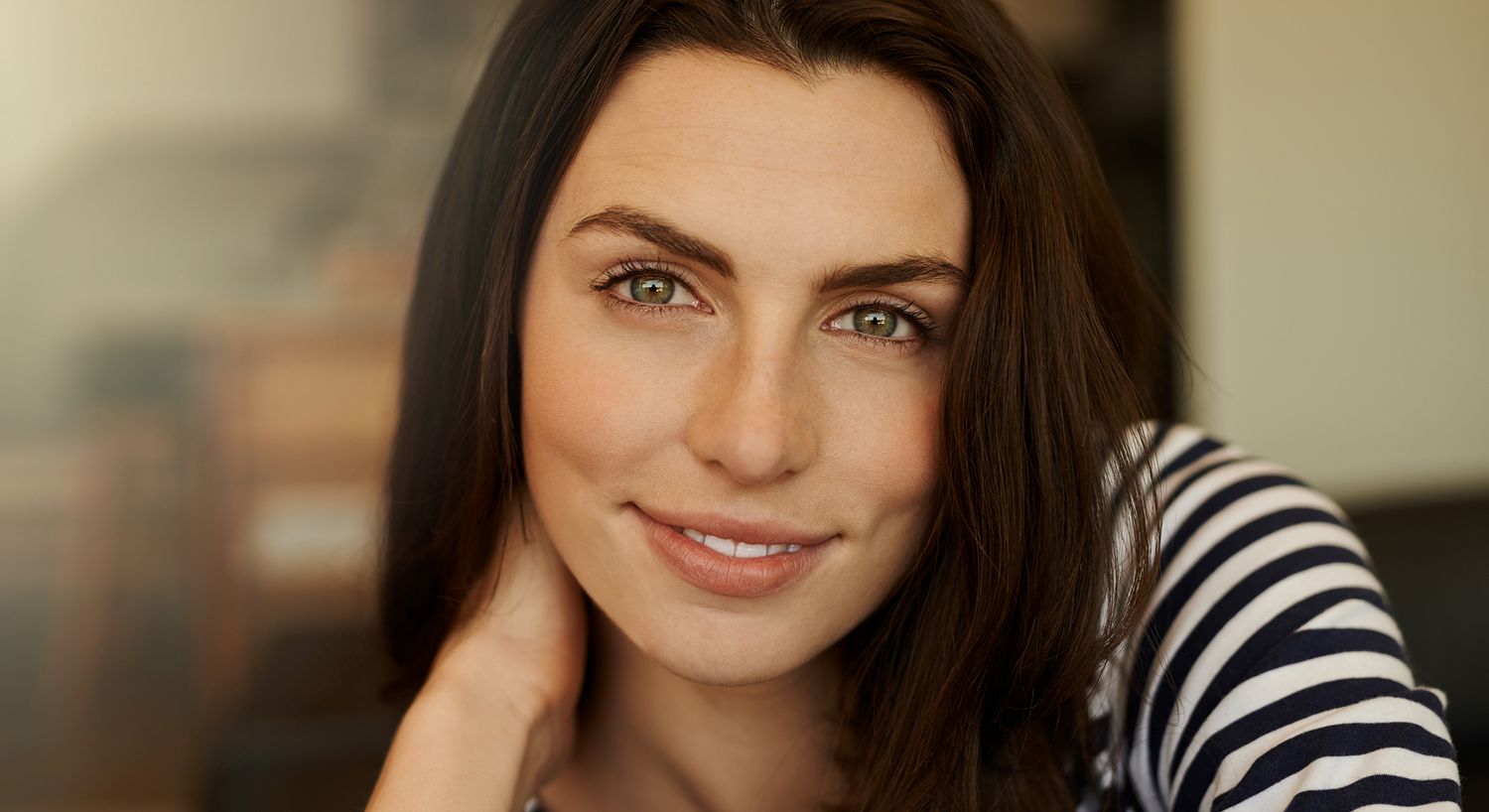 Smiling woman with long dark hair indoors.