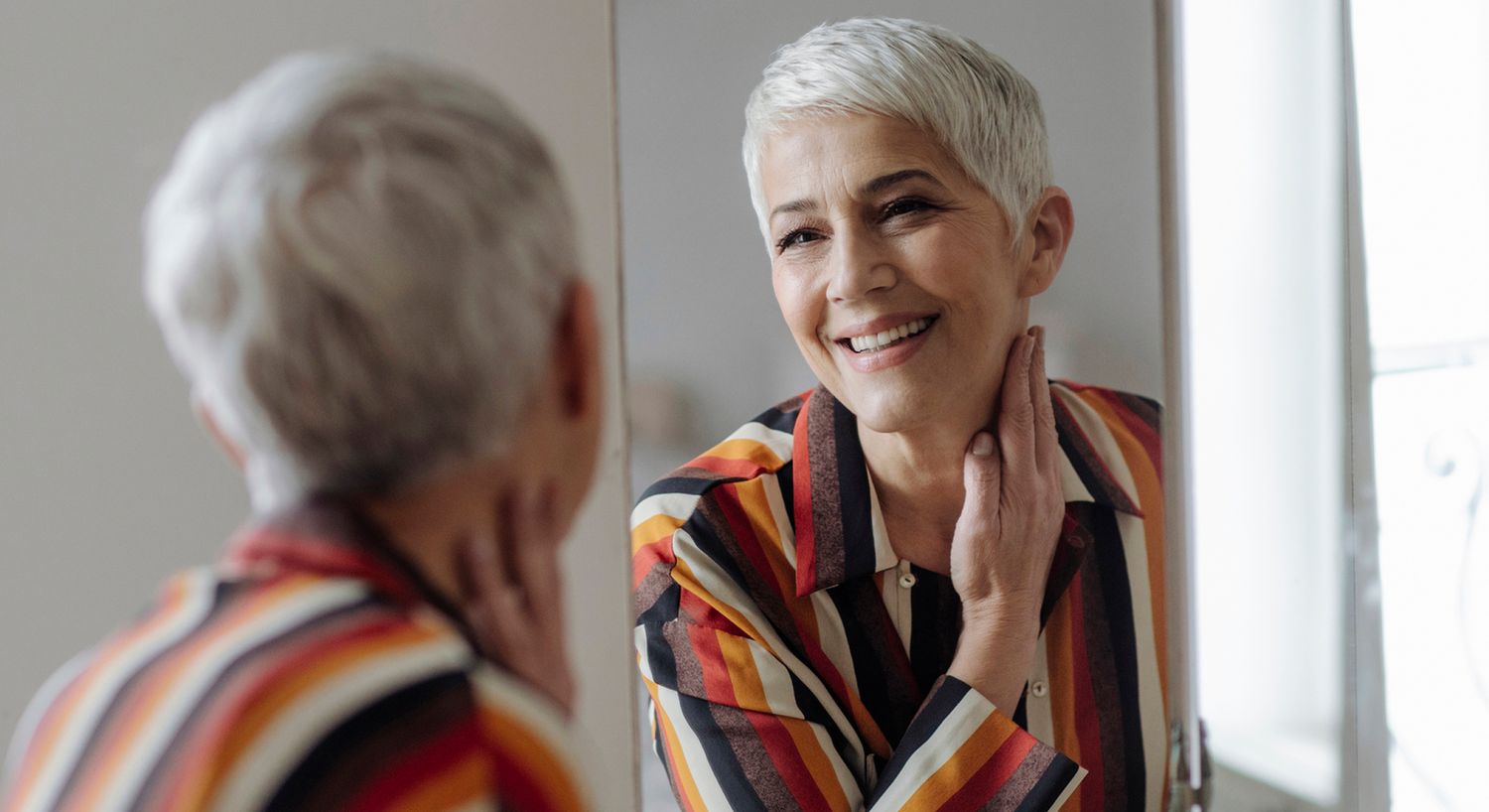 Woman smiling at her reflection in mirror.