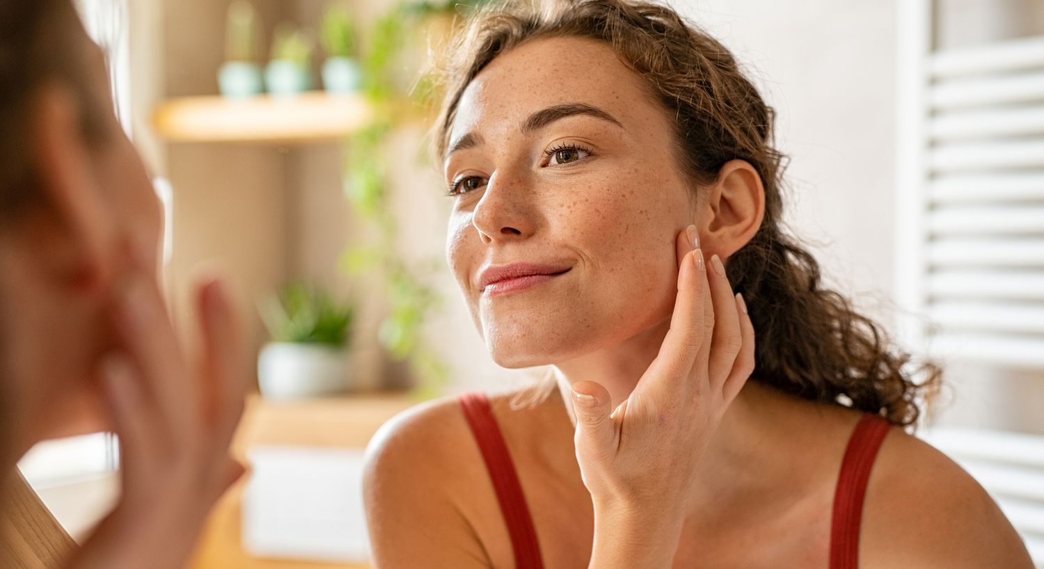 Woman applying skincare while looking in mirror