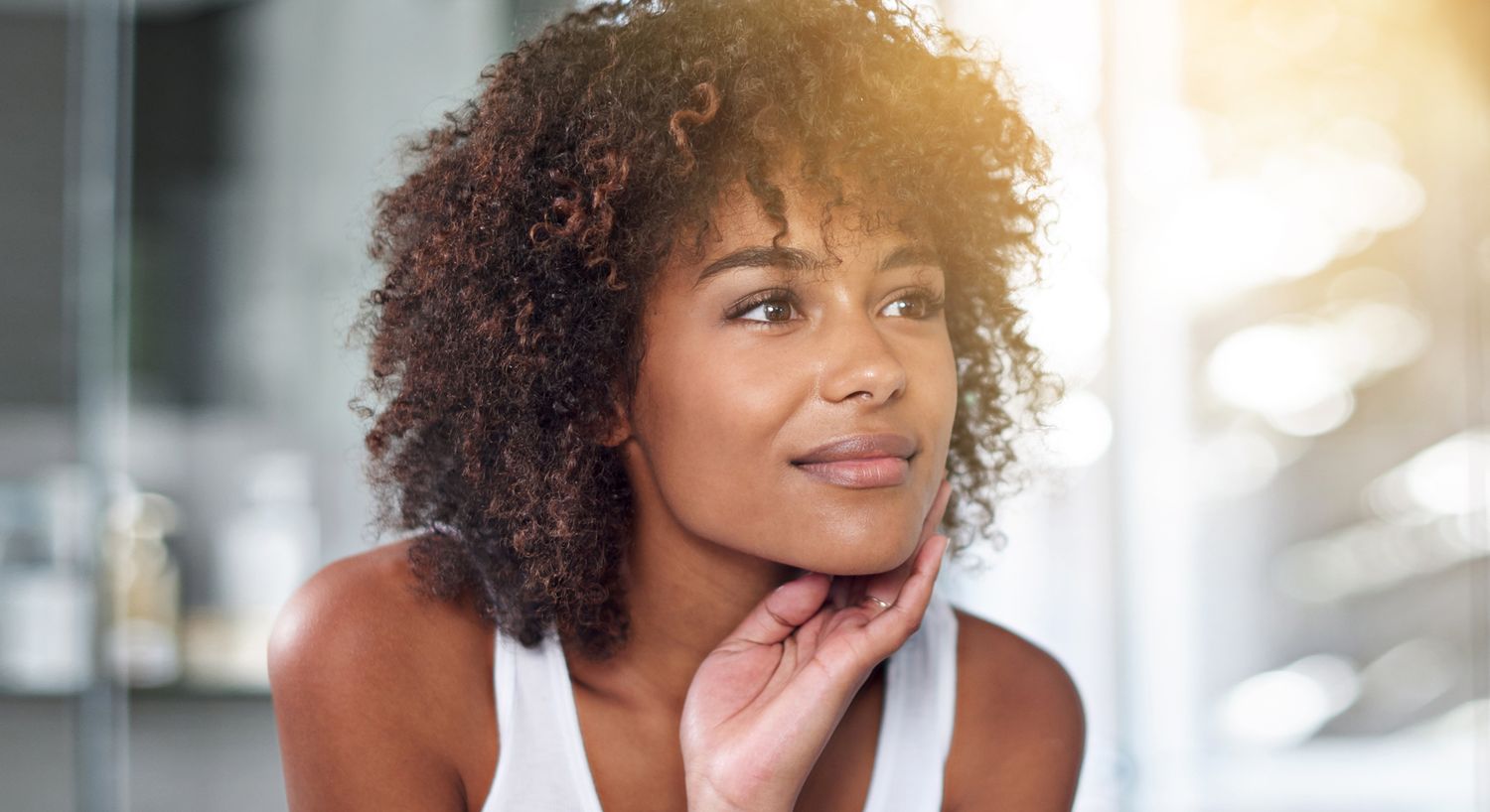 Contemplative woman with curly hair indoors.